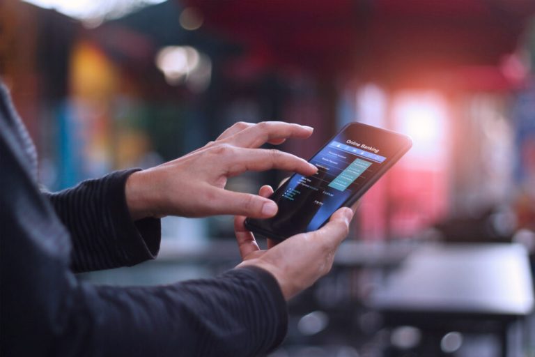 Man using mobile smartphone for online banking in cafeteria